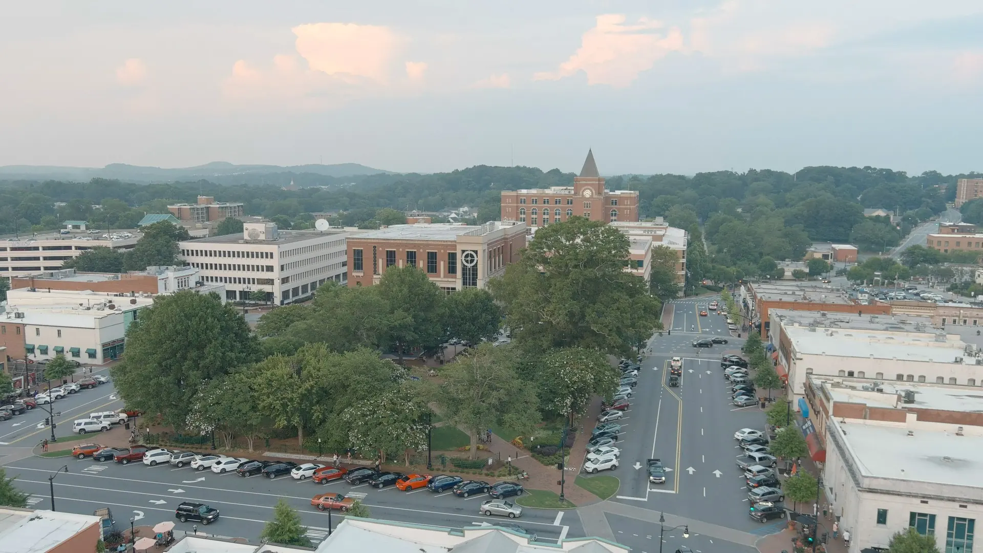 Downtown Marietta from above at dusk: the Square's trees, the courthouse clock tower and the hills of Cobb County beyond