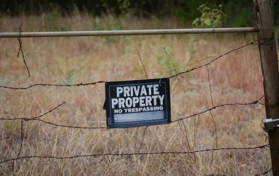 A private property sign hung on a wire fence in a dry field